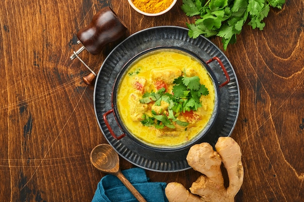 Chicken Tikka Masala. Traditionell der indischen Küche Curry und Zutaten auf dunklem Hintergrund. Curry, Limette, Ingwer, Koriander, Chili, Reis, Kräuter und Gewürze. Draufsicht mit Kopienraum.