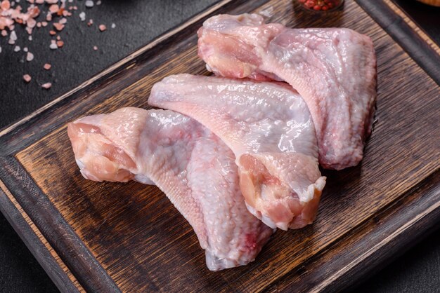 Chicken Wings liegen auf einem Holzbrett auf schwarzem Hintergrund