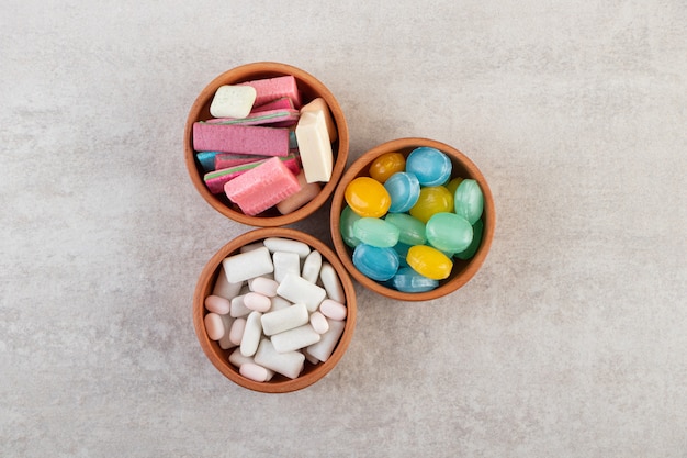 Chicles de colores en cuencos de arcilla colocados sobre la mesa de piedra.