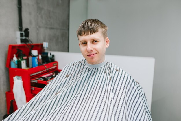 Foto chico adolescente corta el pelo en el retrato de la peluquería en el interiorconcepto de peluquería