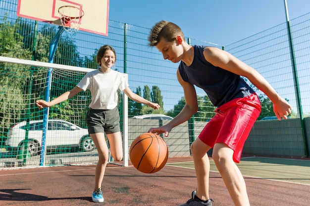 Chico adolescente entrenando a su novia jugando baloncesto, juego de baloncesto callejero