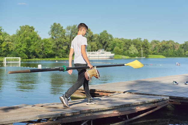 Chico adolescente montando con paleta para kayak deportivo