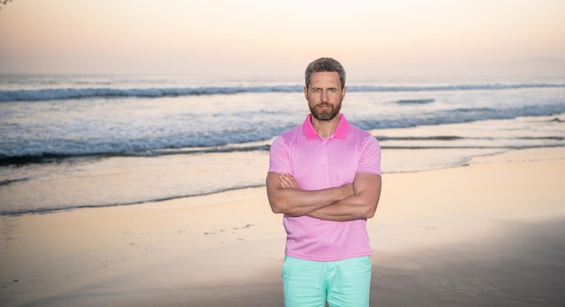 Chico sin afeitar en la playa de la mañana chico caucásico en la playa del amanecer hombre barbudo en camisa