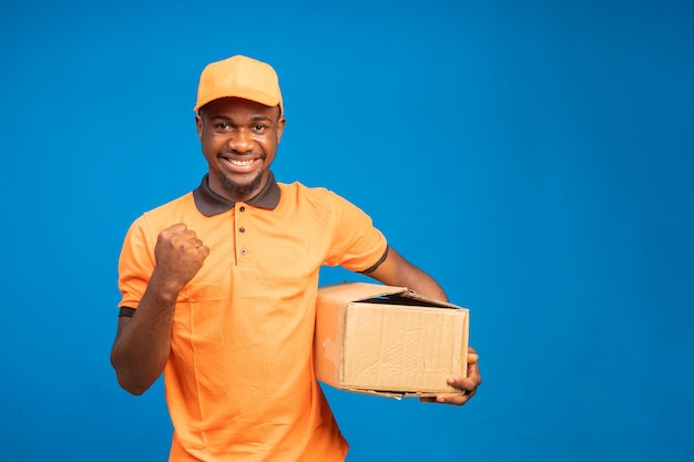 Chico africano guapo que se siente emocionado mientras sostiene el paquete de entrega en su mano