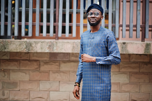 Chico africano en traje azul auténtico, anteojos y boina. Hombre nigeriano de moda.