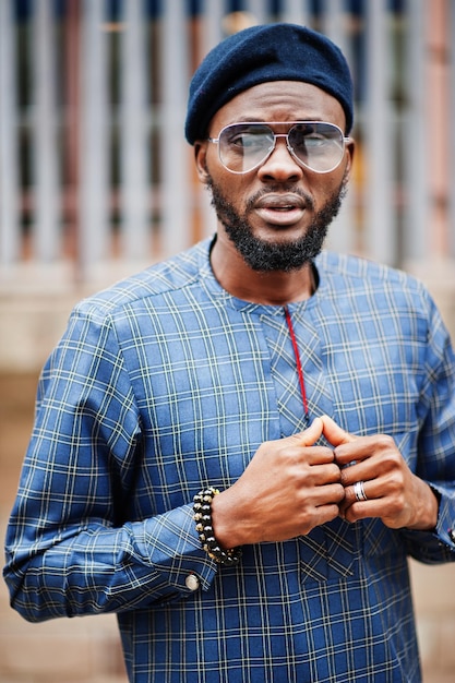 Chico africano en traje azul auténtico, anteojos y boina. Hombre nigeriano de moda.