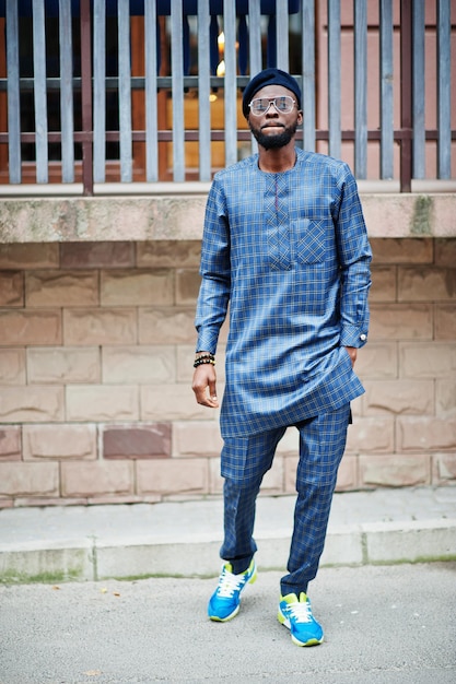 Chico africano en traje azul auténtico, anteojos y boina. Hombre nigeriano de moda.