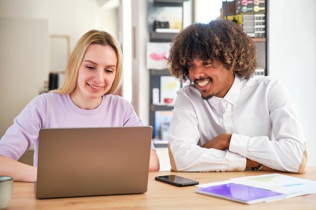 Chico afroamericano con cabello afro y chica caucásica rubia de pelo largo en un coworking