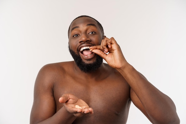 Chico afroamericano enfermo comiendo píldora de medicina hombre negro de pie sobre fondo liso con espacio de copia