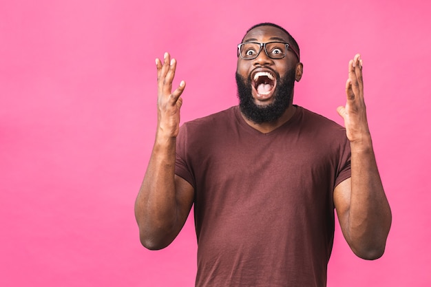 Chico afroamericano sorprendido sorprendido en casual aislado en retrato de estudio de fondo rosa. Concepto de estilo de vida de personas. Simulacros de espacio de copia. Manteniendo la boca abierta.