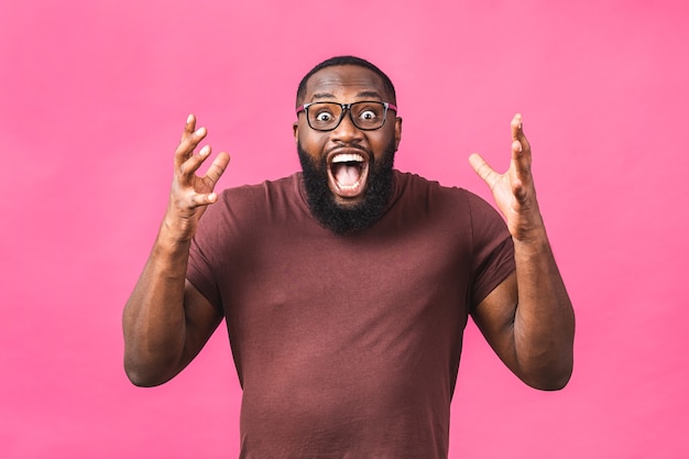 Chico afroamericano sorprendido sorprendido en casual aislado en retrato de estudio de fondo rosa. Concepto de estilo de vida de personas. Simulacros de espacio de copia. Manteniendo la boca abierta.