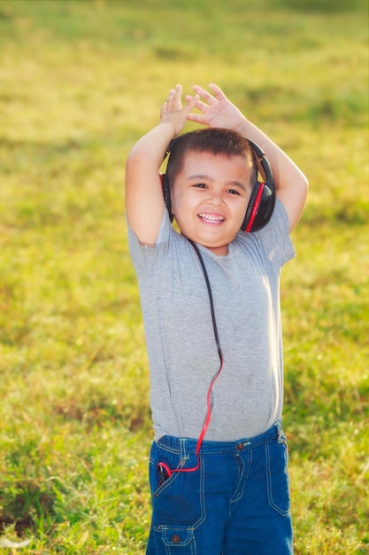 El chico alegre en el parque matutino y al aire libre