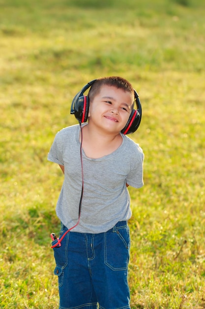 El chico alegre en el parque matutino y al aire libre