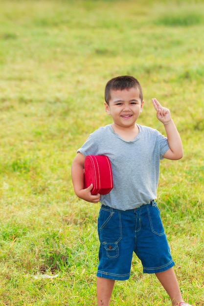 El chico alegre en el parque matutino y al aire libre