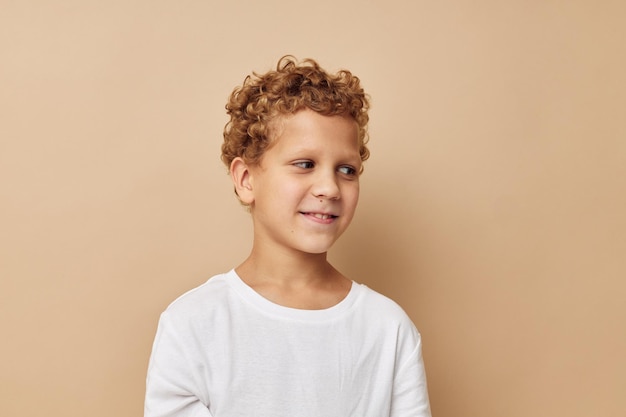 Chico alegre con el pelo rizado en una camiseta blanca de fondo beige