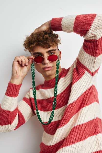 Chico alegre con el pelo rizado en elegantes gafas posando