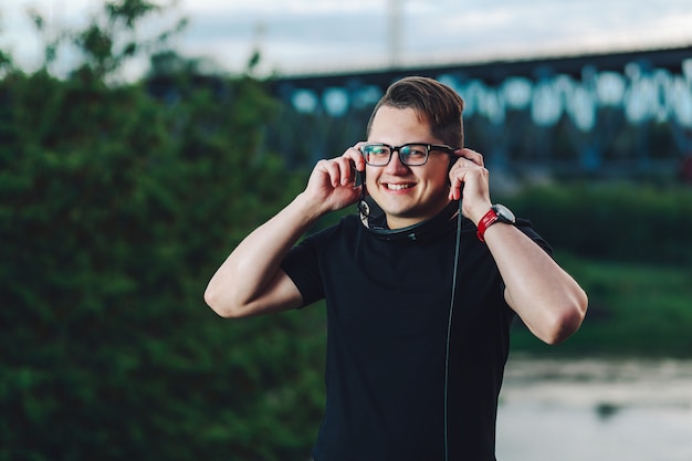 Chico alegre sonriente posando con auriculares al aire libre