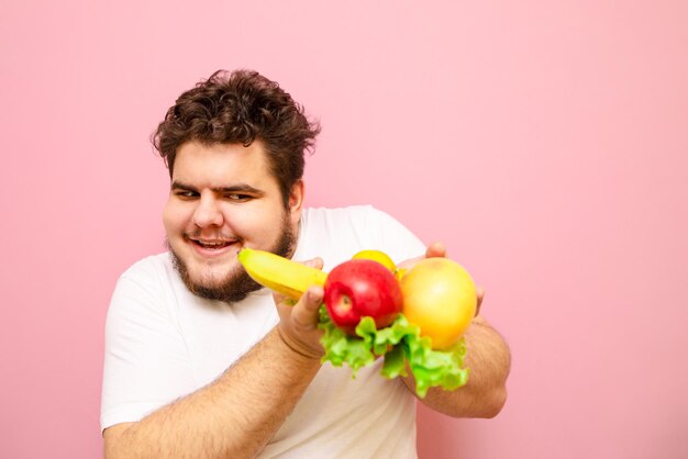 Chico alegre con una sonrisa en su rostro tiene fruta en sus manos