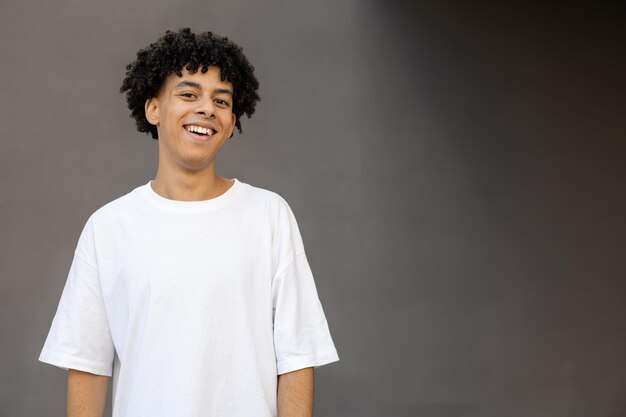 Foto chico americano feliz sonriendo por las buenas noticias usando una camiseta blanca