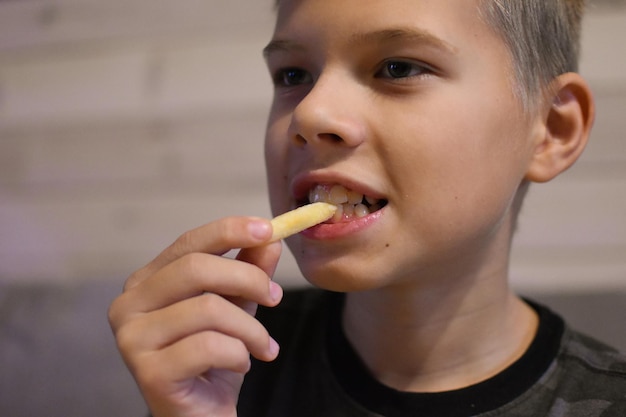 El chico con apetito come papas fritas. niño comiendo comida rapida