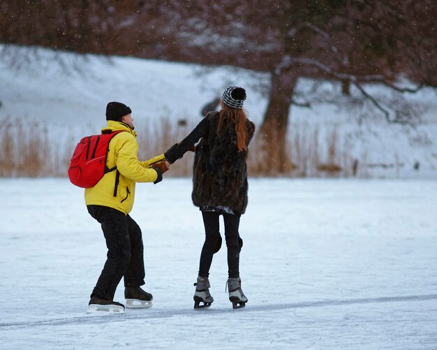 Chico aprendiendo a su chica Patinaje sobre hielo en un lago cubierto de hielo en invierno Trakai. El patinaje es cualquier actividad que consiste en viajar sobre hielo utilizando patines.