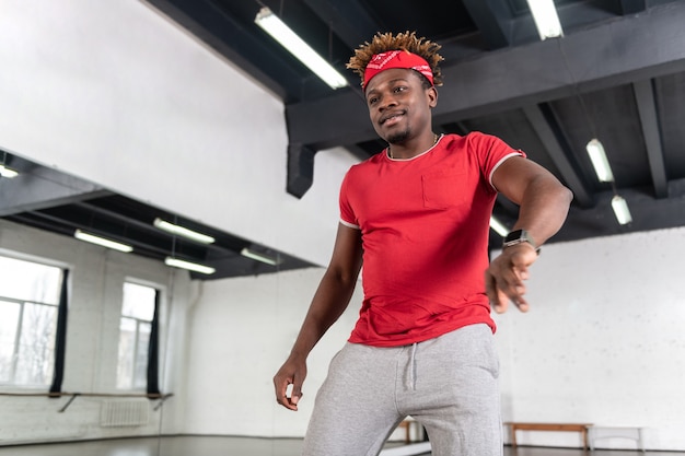 Chico apuesto alegre con rastas cortas bailando en el estudio de danza de estilo moderno