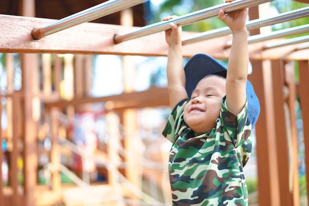 Chico asiático de 1 año y 9 meses en traje militar jugando en el área de entrenamiento para niños