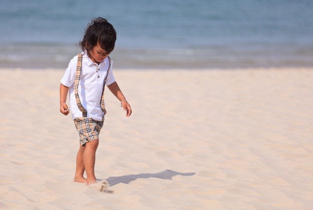 Chico asiático caminando en la playa tropical