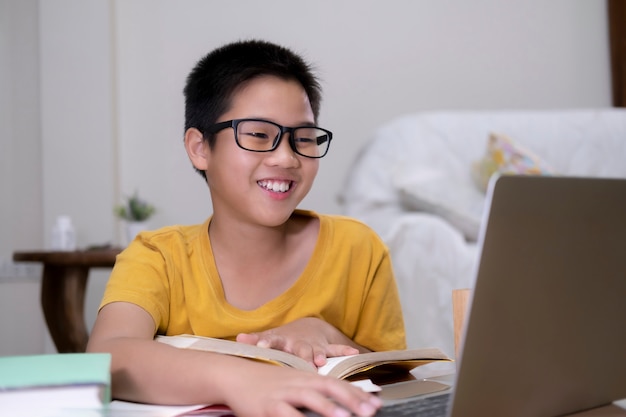 Chico asiático disfruta de autoestudio con e-learning en casa