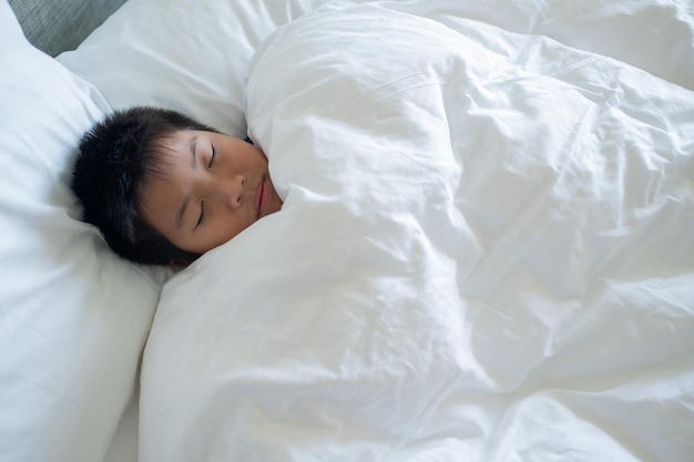 chico asiático dormir en la cama niño enfermo dormir