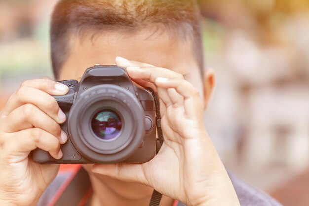 Chico asiático fotografiando con cámara réflex negra