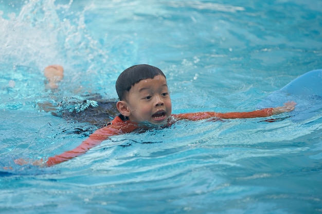 Foto chico asiático nadando en la piscina de agua