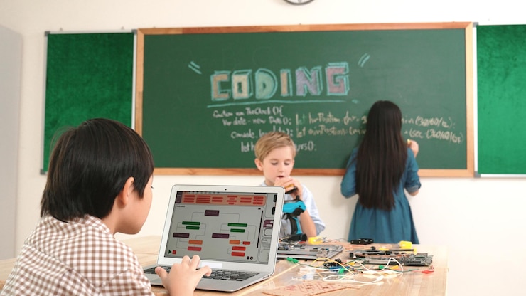Foto un chico asiático programando mientras un amigo arregla la tabla eléctrica en la clase de pedagogía.