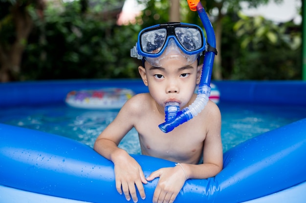 chico asiático con snorkel en la piscina