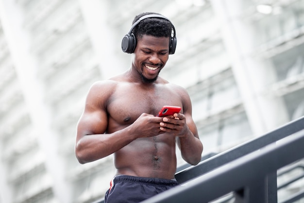 Chico atlético afroamericano escucha música al aire libre en verano hombre sin camisa