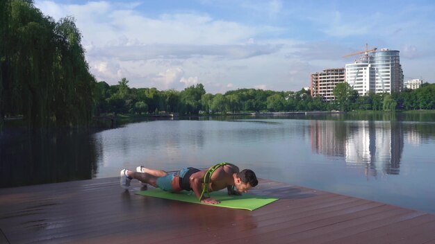 Chico atlético con el pecho desnudo haciendo flexiones en la estera de yoga