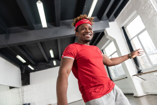 Chico atractivo en camiseta brillante bailando en el estudio y participando en la acción