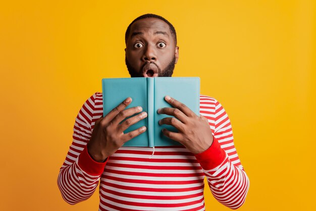 Chico atractivo estudiante sorprendido leer libro con la boca abierta