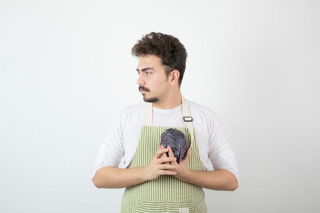 Chico atractivo joven sosteniendo repollo y mirando a otro lado.