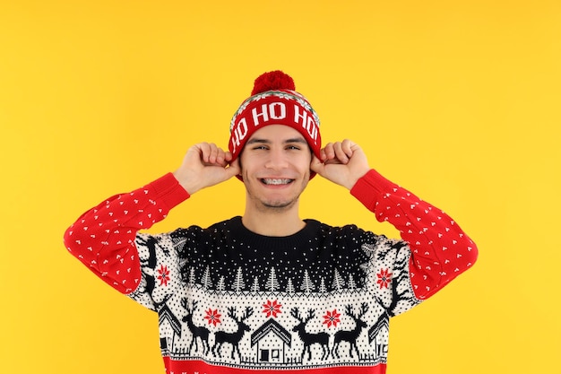 Chico atractivo en suéter de Navidad sobre fondo amarillo