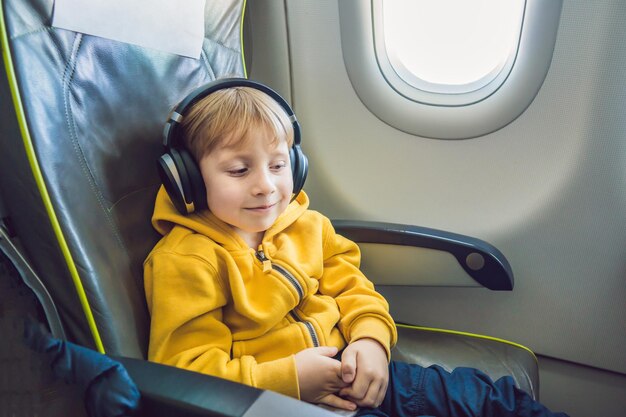 Chico con auriculares viendo y escuchando entretenimiento en vuelo a bordo del avión