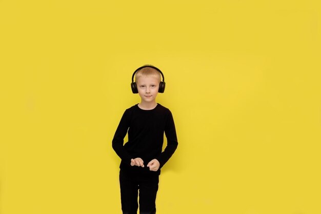 Chico bailando en auriculares sobre un fondo amarillo con espacio de copia