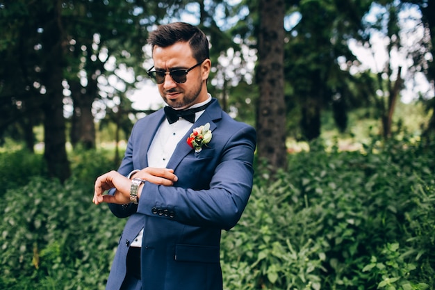 chico con barba en gafas de sol. joven con traje y corbata de moño.