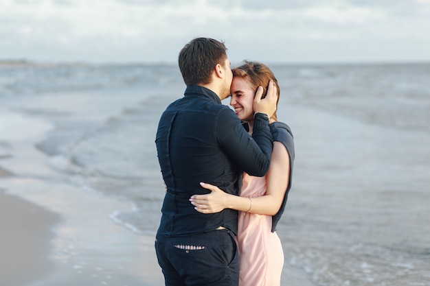 Foto chico besando a su chica contra el mar