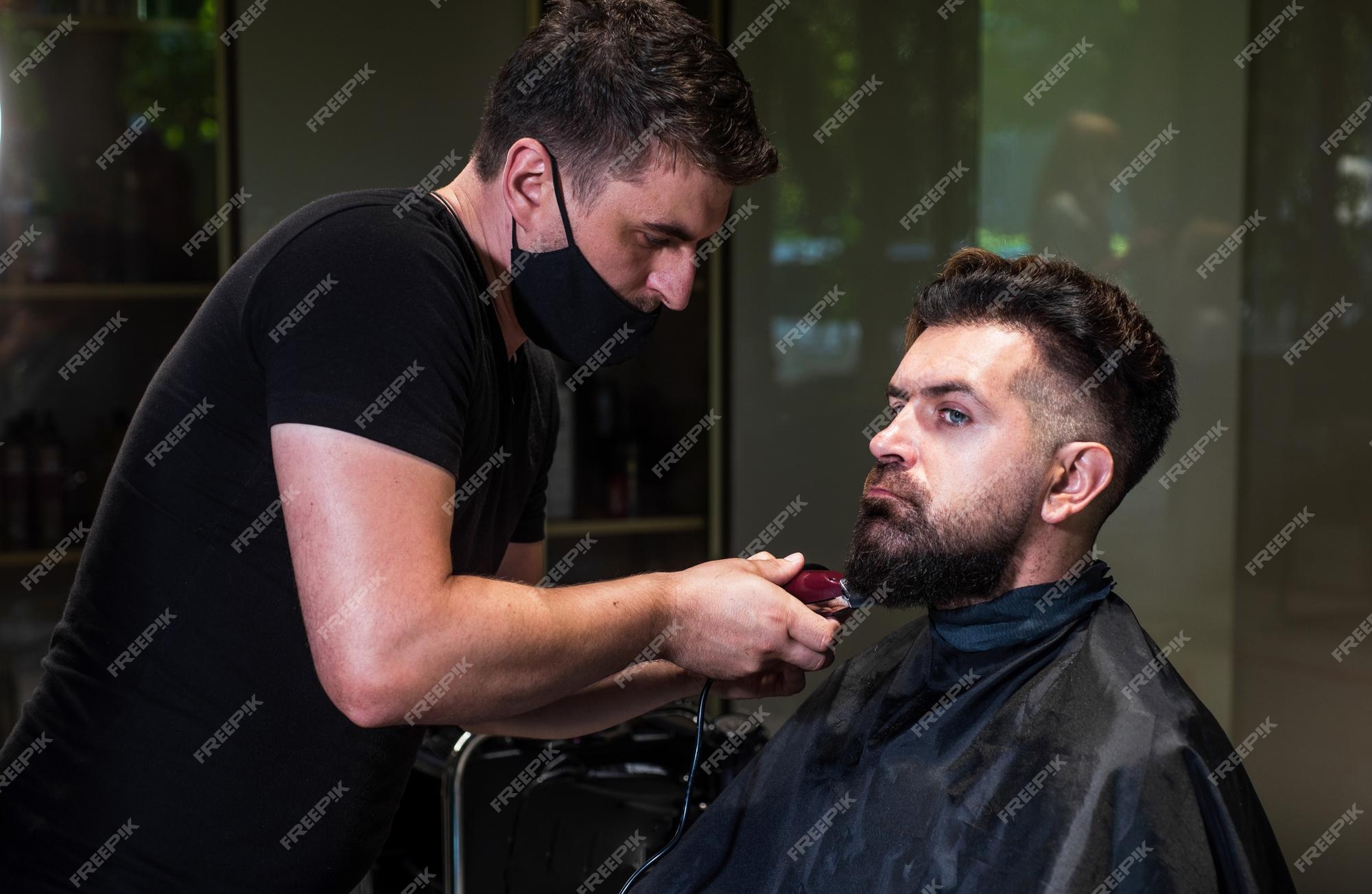 mapa despensa nombre de la marca Chico brutal de aspecto mágico con maestro profesional de barbería uso de  máquina de afeitar eléctrica hipster hombre barbero cuidado hombre barbudo  en la silla de peluquería en el salón de belleza