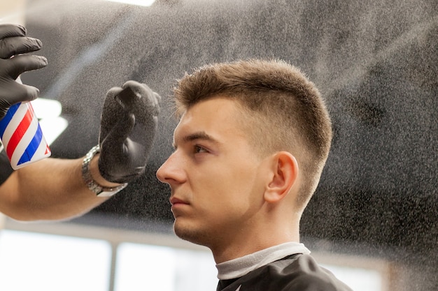 Foto chico brutal en la moderna peluquería. peluquero hace peinado un hombre. maestro peluquero hace peinado con cortapelos. concepto de peluquería