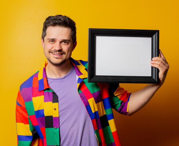 Chico en camisa de los 90 con marco de fotos