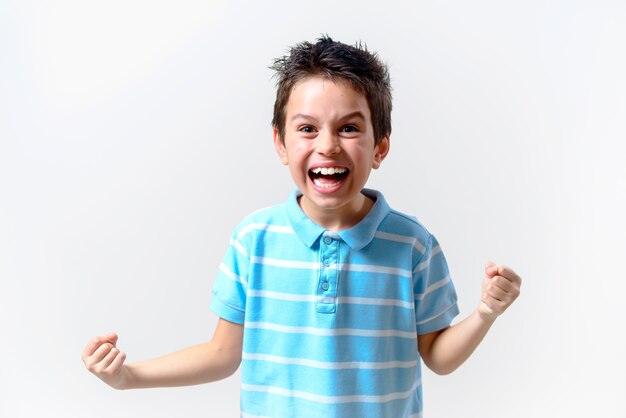 El chico de camiseta azul hace una mueca cruel con los puños cerrados.