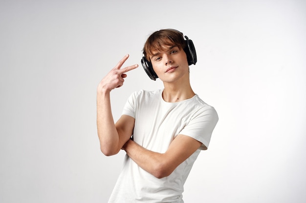 Chico en camiseta blanca con fondo claro de tecnología de música de auriculares