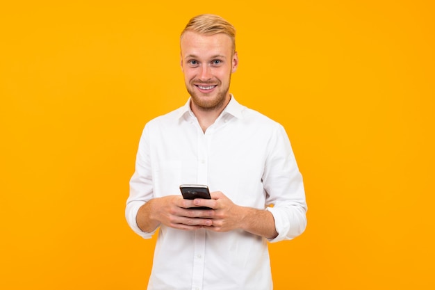 Chico con una camiseta blanca con un teléfono celular en la mano